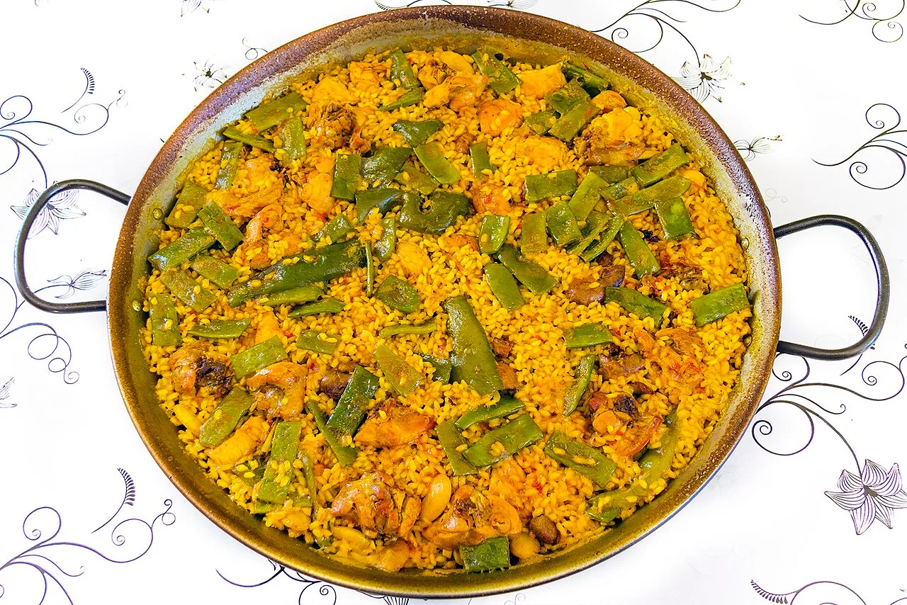 Паэлья валенсиана на сковороде: жёлтый рис, плоская фасоль, курица и кролик